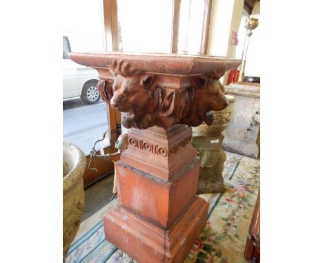A large terracotta jardinière with lion mask head decoration, on square pedestal base