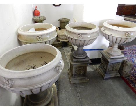 Four concrete garden urns with flower form borders, on circular pedestals, raised on Art Nouveau design square bases