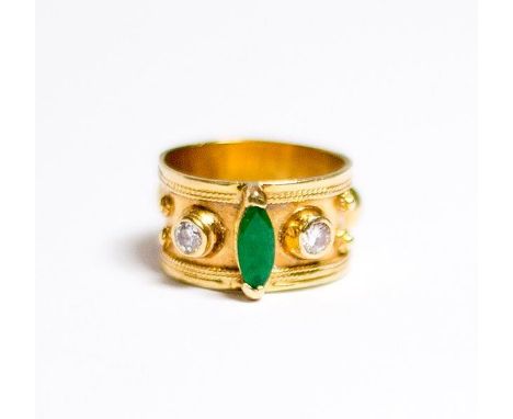 A gold Etruscan style ring set oval emerald flanked to each side by diamonds