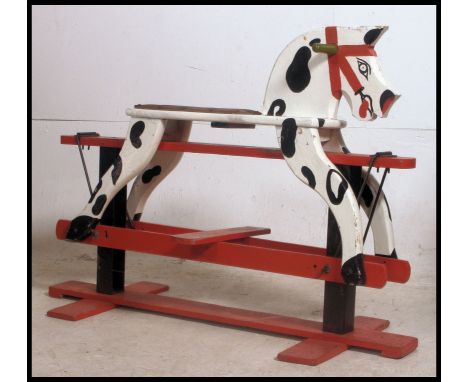 A vintage mid century painted childs rocking hours in red and white with dappled effect. All over raised red glider base