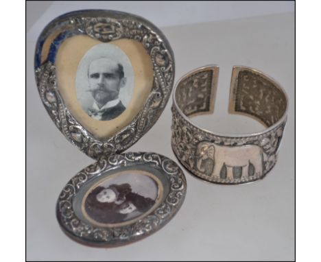 Two silver hallmarked silver easel picture frames, the first being circular and the other being shaped like a heart along wit