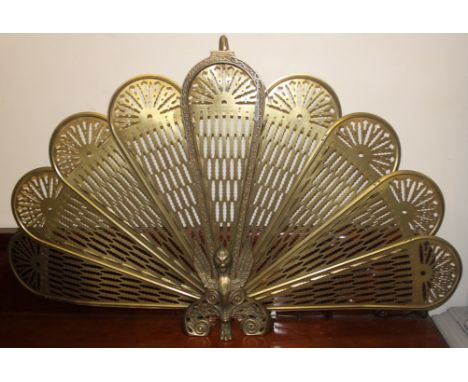 A 20th Century brass metamorphic peacock firescreen having eight fan out leaves with a Griffin base in working order with all