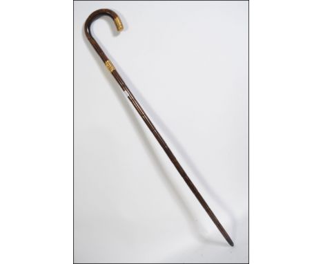 A 20th century walking stick  having a 18ct  gold plated  metal  collar and brass feral H91cm