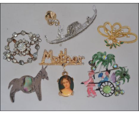 A collection of 7 vintage brooch pins to include white metal long ship brooch, yellow metal Mother brooch with hanging cameo,