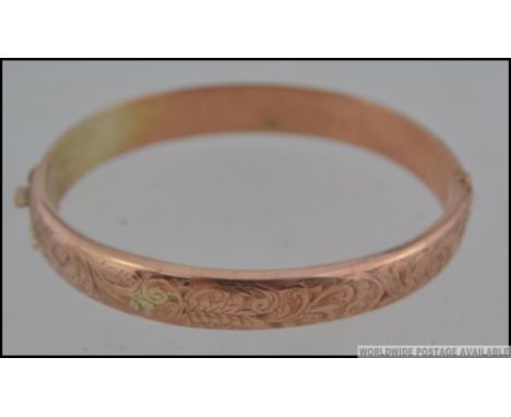 A hallmarked 9ct gold bangle bracelet with foliate scroll decoration with clip and safety clasp. Hallmarked for Birmingham 19