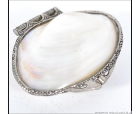 A silver white metal and mother of pearl purse, having decorative scroll work metal with a hinged lid. Measures: 12cms long.