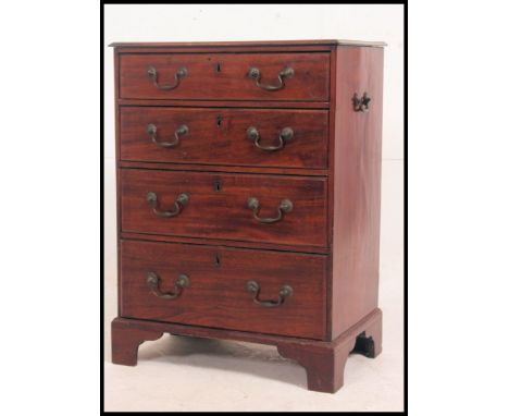 A Georgian bachelors mahogany chest of drawers of small proportions. The chest with side handles having a bank of drawers bei