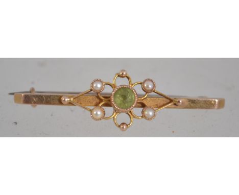 A 15ct gold and peridot set ladies bar brooch with seed pearl borders having pin to verso. Stamped 15k. Total weight 2.0g
