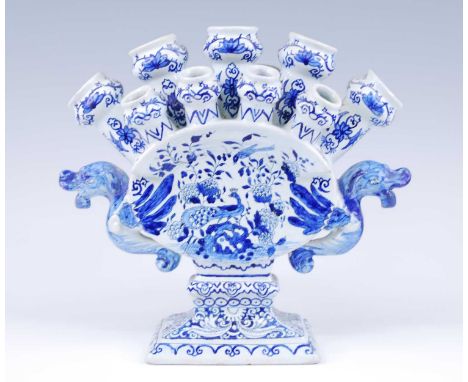 A Delft blue and white tulipiere, the thirteen tulip nozzles flanked by twin dragon handles, decorated with peacocks amongst 