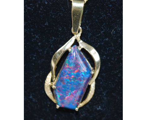 A yellow metal abstract opal doublet pendant, comprising an approx 22 x 10mm black opal doublet claw set within an open scrol