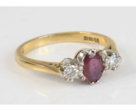 A modern 18ct gold, ruby and diamond three-stone ring, arranged as a centre oval cut ruby flanked to either side with a singl