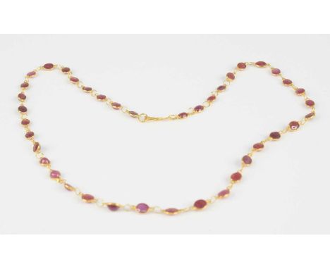 A yellow metal ruby multi-stone necklace, having forty oval cabochon cut rubies in bezel settings, with figure of eight clasp