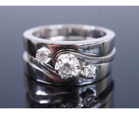 Three white metal diamond stacking rings, each with a round brilliant cut diamond claw set within a shaped mount, diamond dim