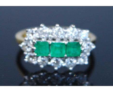 An 18ct yellow and white gold, emerald and diamond triple cluster ring, comprising three central square cut emeralds within a