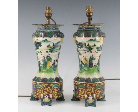 A pair of Chinese famille verte table lamps, each of baluster form upon figural supports, flanked by shishi mask handles and 