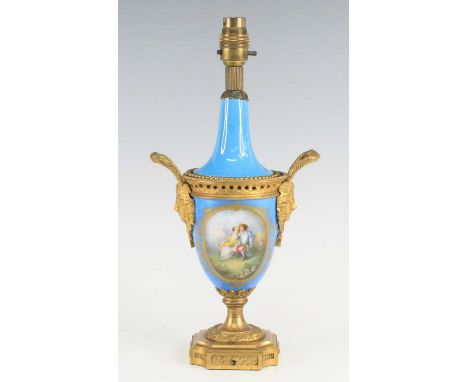 A French porcelain and gilt metal table lamp, early 20th century, of baluster form, flanked by mask handles, decorated with a