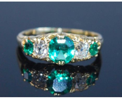 A yellow metal, emerald and diamond five stone half hoop ring, comprising three graduated oval emeralds and two old European 