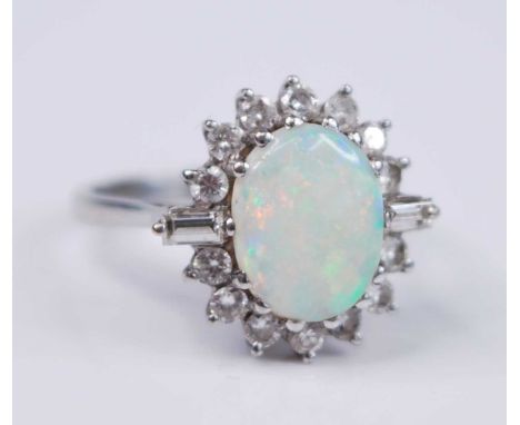 A white metal, opal and diamond oval cluster ring, comprising a centre oval cabochon cut opal within a border of fourteen rou