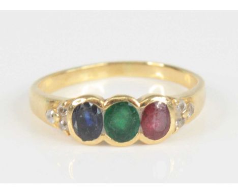 A yellow metal multi-stone dress ring, comprising an oval ruby, emerald and sapphire all in bezel settings, with a trefoil of