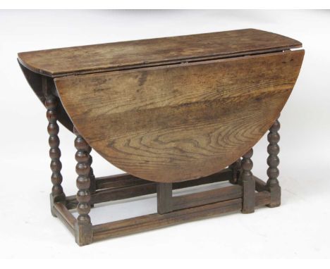 An antique joined oak gateleg table, the probably associated top having oval fall leaves above an end frieze drawer, raised o