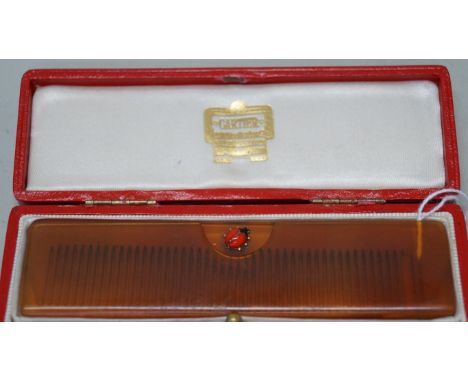 A Cartier celluloid and enamel comb and case, circa 1950s, applied with a ladybird to each side, 115cm wide, in original cart