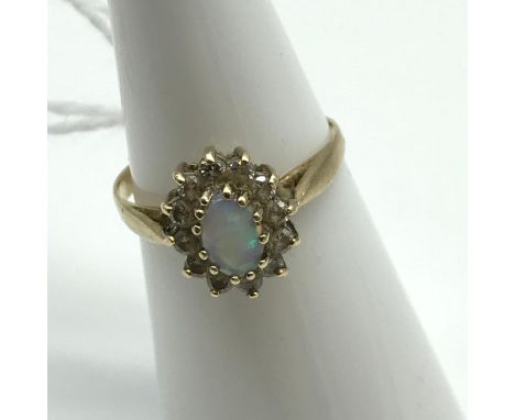 A Ladies 9ct gold ring set with a single opal stone surrounded by clear glass stones. Ring size K and weighs 1.6grams