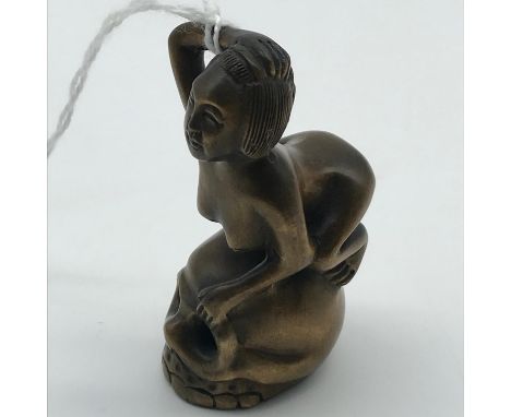 A Highly detailed Japanese netsuke figure of a Nude Geisha sat upon a skull. Signed by the artist.