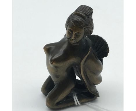 A Highly detailed Japanese netsuke figure of a nude geisha dancing with fan. Signed by the artist to the base of the leg.