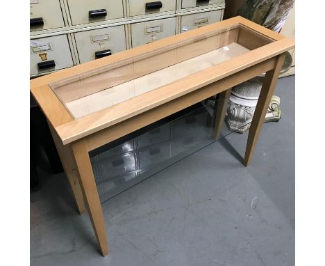 A Contemporary light wood and glass console table. Has a lift off top for display items. Measures 70x90x30cm 