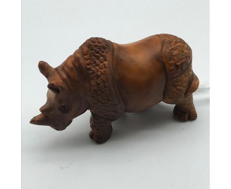 A Highly detailed Japanese hand carved netsuke figure of a Rhino, detailing black bead eyes and signed to the back leg by the