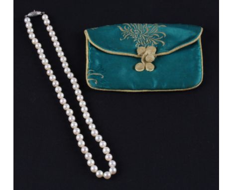 A standard short string of cultured pearls, clasp stamped Silver, housed in a silk purse, (A/F pearl missing to clasp).