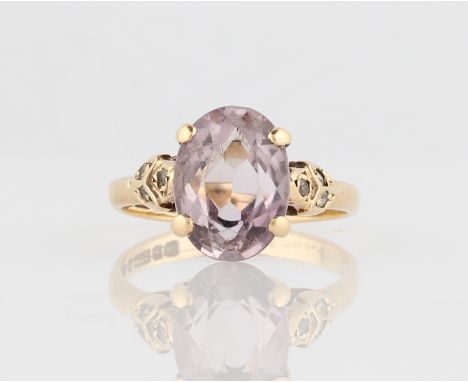 A hallmarked 9ct yellow gold amethyst ring, set with an oval cut amethyst flanked to either side with colourless stone accent