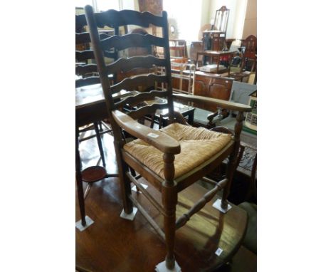 A pair of reproduction beech wood ladder back elbow chairs, each with an envelope rush seat.