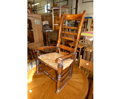 A 19th Century beech wood ladder back rocking chair with an envelope rush seat.
