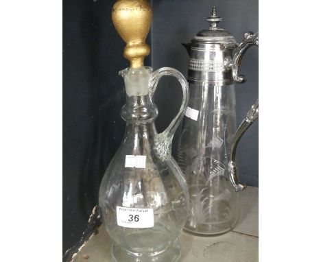 An early 20th Century white metal mounted claret jug of tapering form with etched fern decoration along with a second decante
