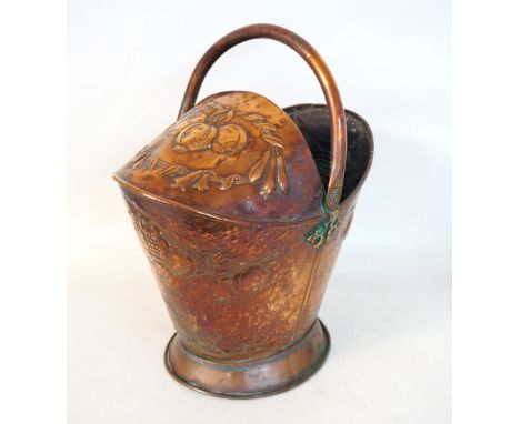 ARTS AND CRAFTS HAMMERED COPPER COAL SCUTTLE
of helmet shape with a swing handle, the body decorated with stylised flower hea