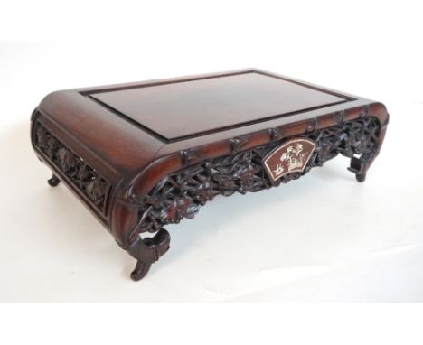 CHINESE CARVED HARDWOOD STAND
with a pierced frieze decorated with vines and mother of pearl inlay, standing on scroll end su