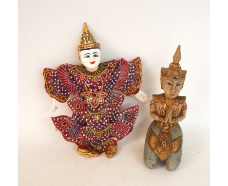 THAI CARVED WOOD PUPPET
in traditional costume, 36cm high, together with a carved woman kneeling with her hands clasped, 32cm