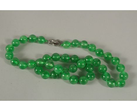 A STRING OF FORTY-FOUR GREEN JADE BEADS with diamond snake clasp.