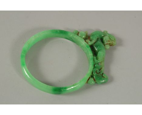 A LARGE JADE BANGLE WITH DOG OF FO. 8cms diameter.