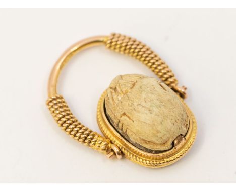 A 20th Century scarab ring, the bone scarab set to the top in a reversible swivel top the underside with hieroglyphics, to a 