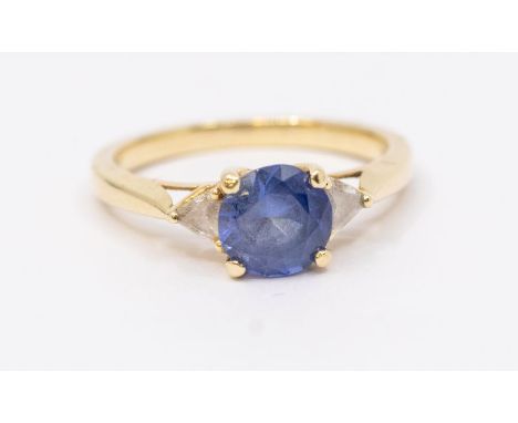 A single stone sapphire and diamond 14ct ring, comprising a round mixed cut claw set sapphire, with trillion diamonds set eit