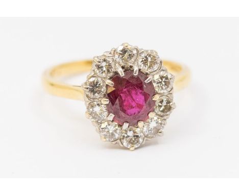 A ruby and diamond cluster 18ct gold ring, comprising a central off round mixed cut ruby weighing approx 1.2carats, within a 