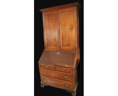 A George II/early George III oak bureau cabinet, stepped cornice above a pair of rectangular doors, fall front enclosing pige