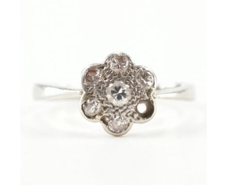 A 1920S 18ct white gold and diamond cluster ring. The ring set with old cut diamonds to a flat cluster setting ( one diamond 