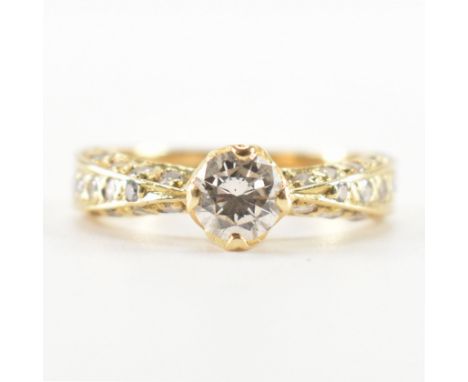 A gold and diamond solitaire ring. The ring being set with a round brilliant cut diamond having pinched shoulders with round 