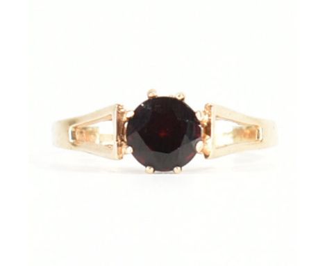 A&nbsp; hallmarked 9ct gold and garnet ring. The ring set with a central mixed cut garnet having split shoulders to plain sha