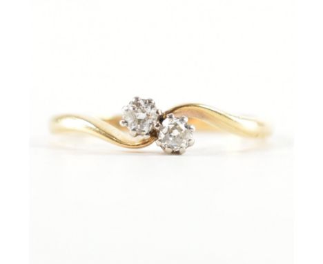 An 18ct yellow gold &amp; platinum crossover diamond ring. The ring having two round cut diamond to undulating pinched crosso