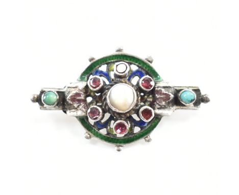 An Austro Hungarian enamel and gem set brooch pin. The brooch set with a central mother of pearl plaque with red and turquois