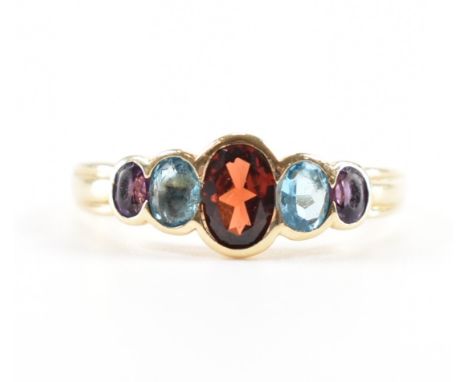 A hallmarked 9ct gold garnet, topaz and amethyst ring. The ring being set with an oval cut garnet flanked by two oval cut ame